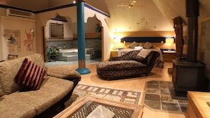 Uma sala de estar aconchegante com um sofá, uma poltrona estampada, uma lareira e um ventilador de teto.