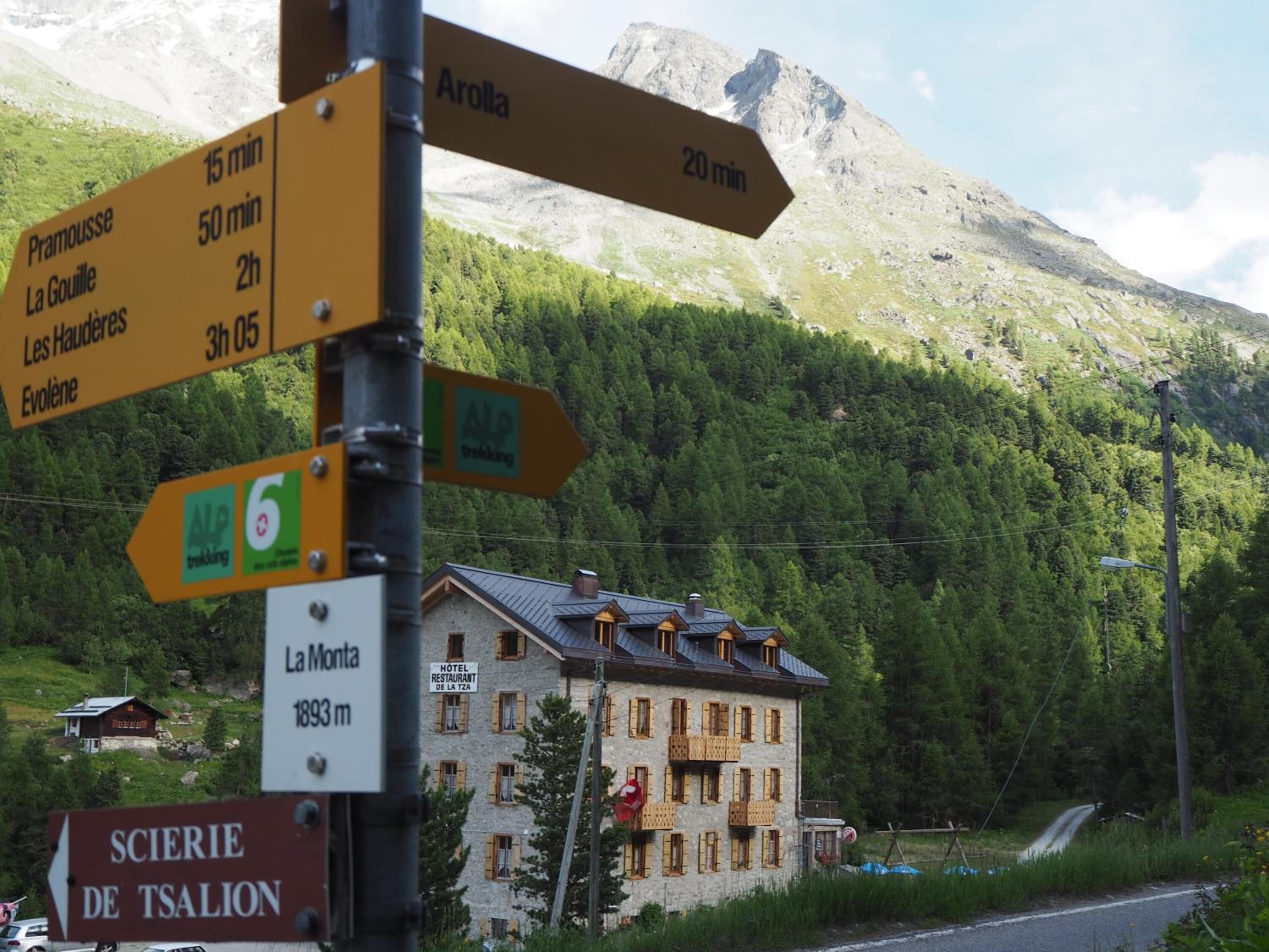 A signpost with directions to various destinations including Arolla, Pramousse, La Gouille, Les Haudères, and Evolène.