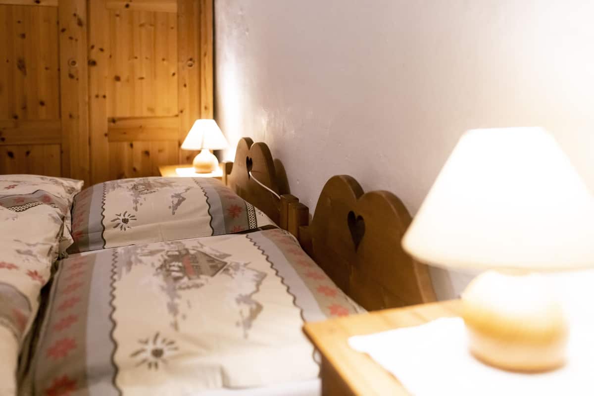 Un dormitorio con cabeceros de madera, una cama con ropa de cama floral y dos lámparas de noche.