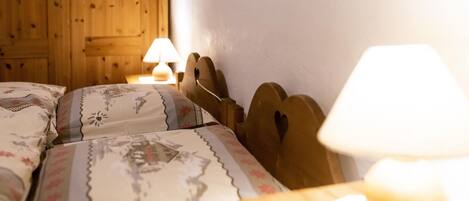 Un dormitorio con cabeceros de madera, una cama con ropa de cama floral y dos lámparas de noche.