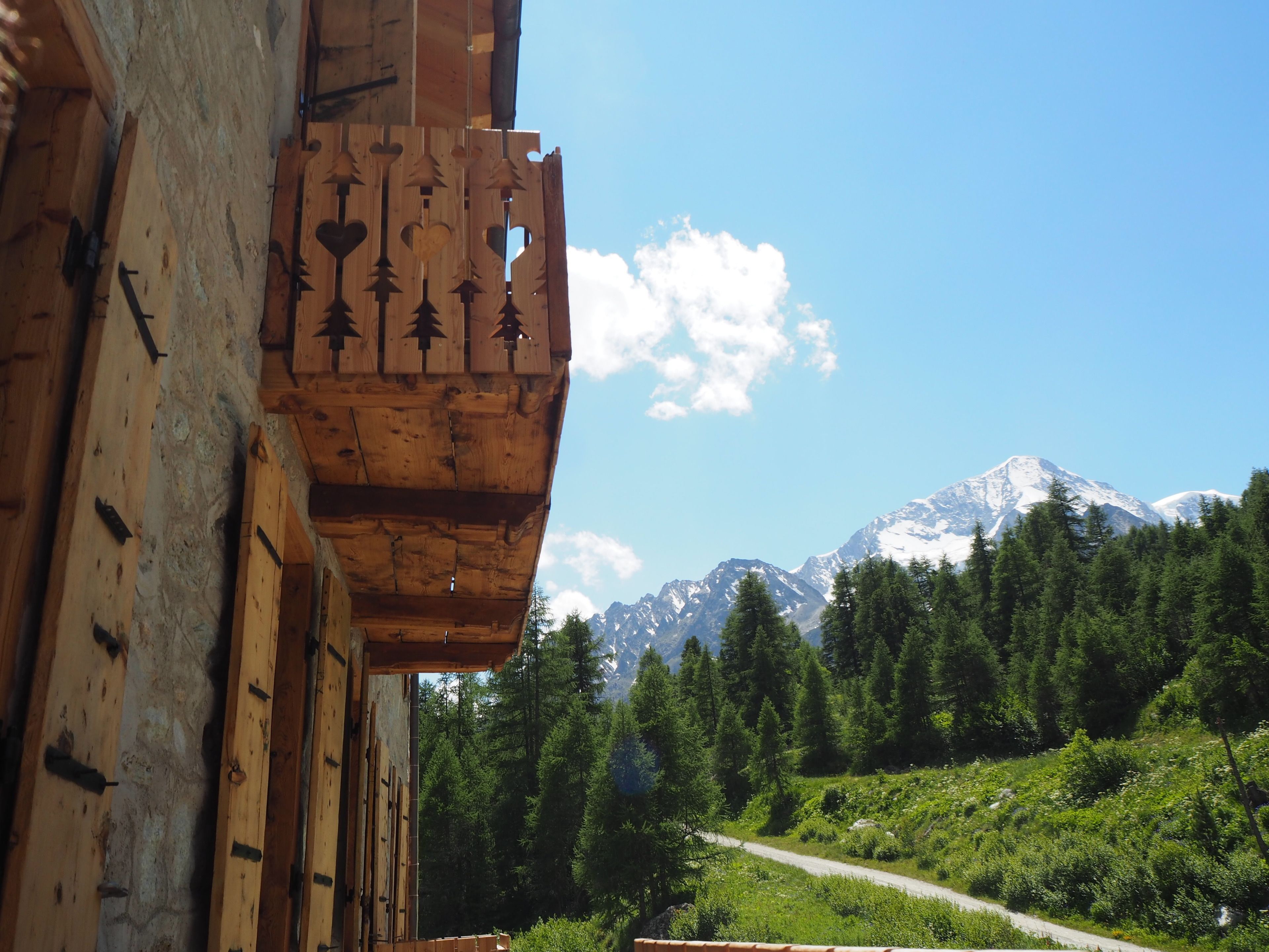 A wooden cabin with a view of a mountain range and a forested area.