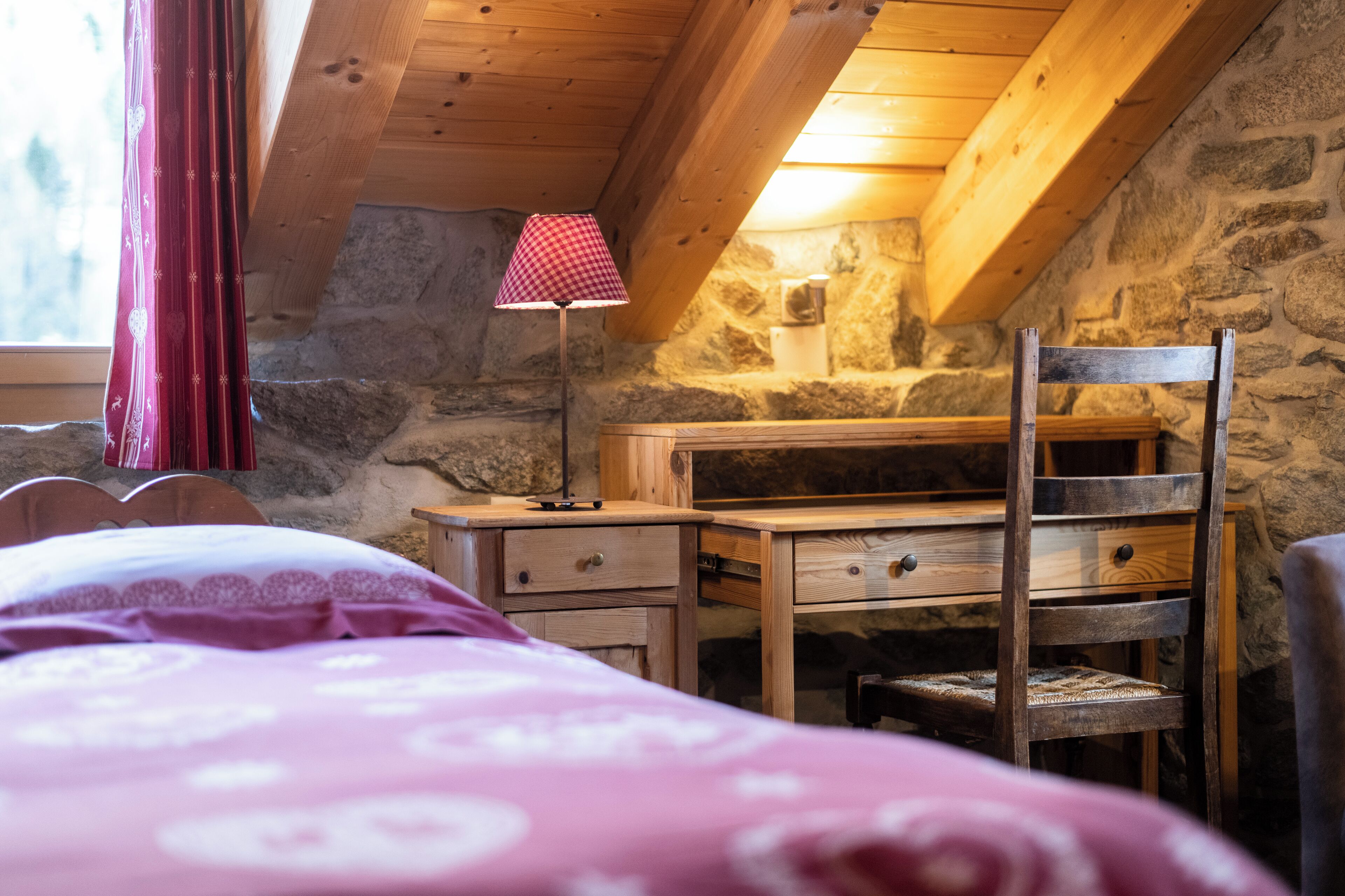 Una habitación acogedora con un escritorio de madera, una silla y una cama con edredón estampado.