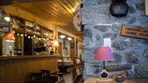 Un rincón de bar acogedor con muebles de madera, paredes de piedra y una lámpara de piedra.