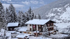 A hotel with a restaurant, surrounded by snow-covered trees and mountains. - Hôtel Restaurant LA CAMBUSE (Vex)