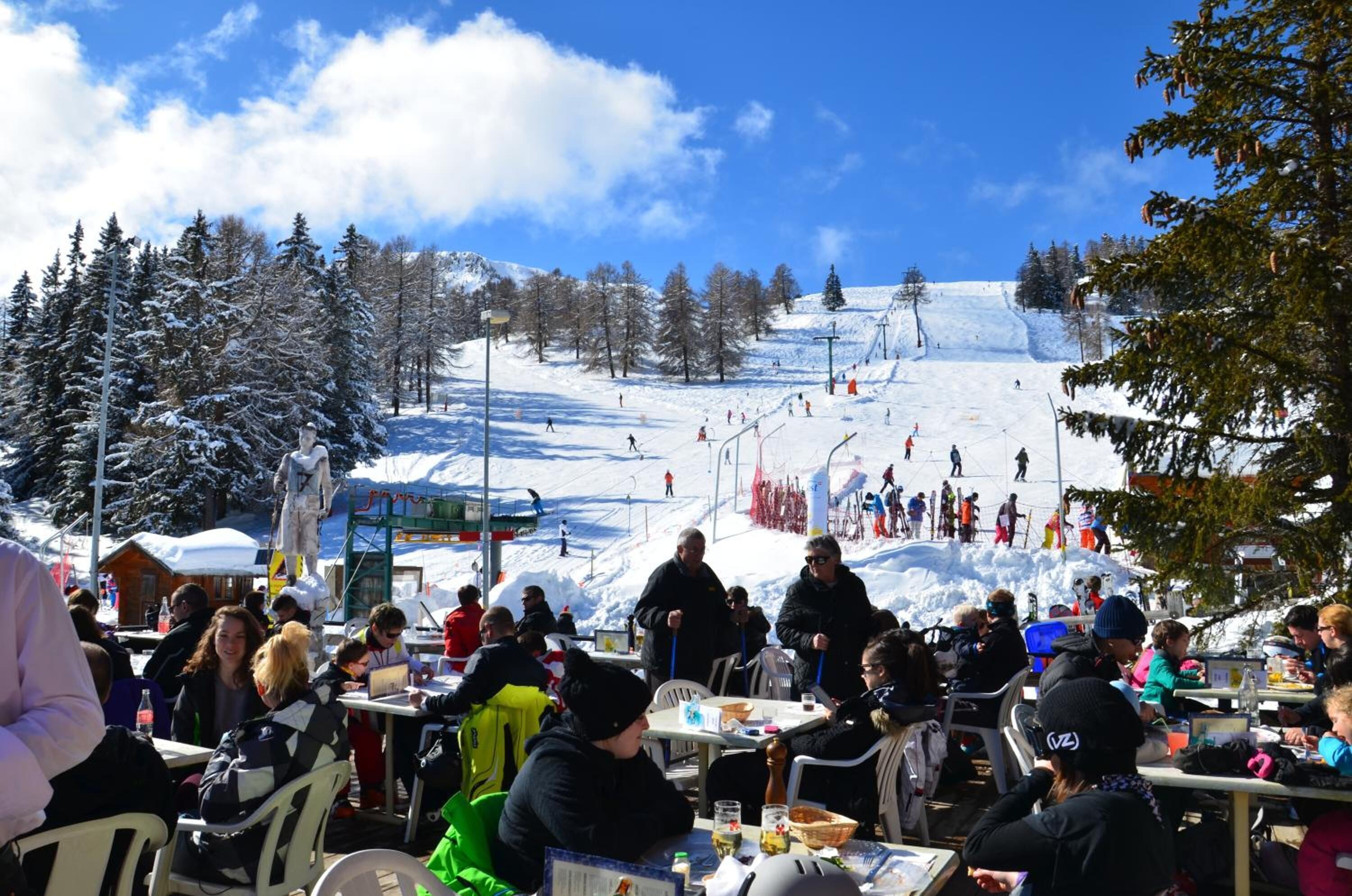 A ski resort with outdoor seating areas overlooking a snowy slope.