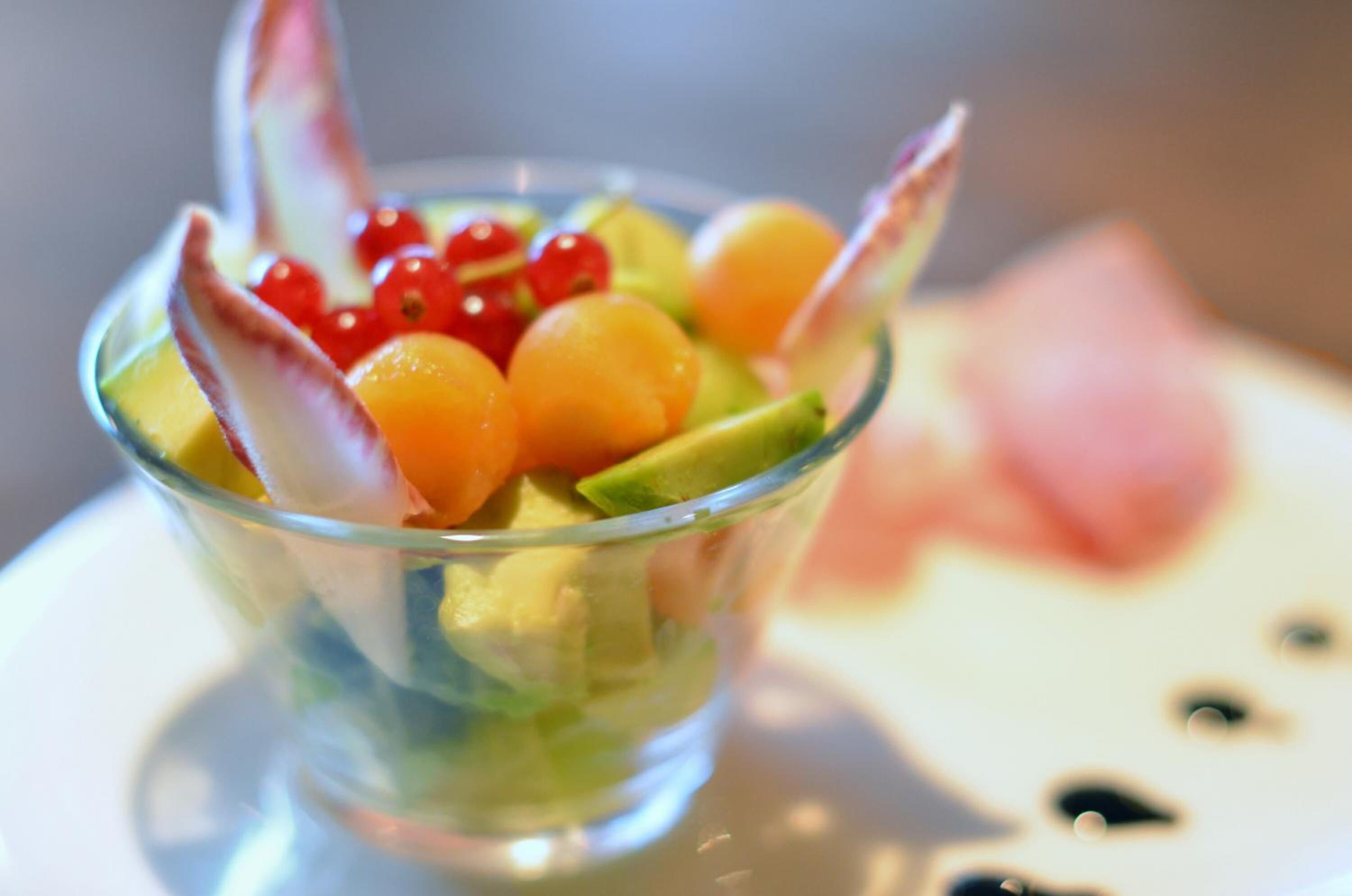 A clear glass bowl containing a fruit salad with various fruits and a decorative element.