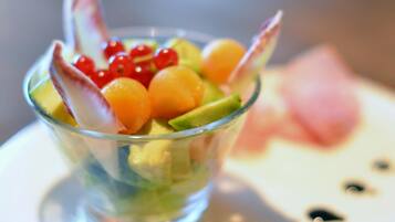 A clear glass bowl containing a fruit salad with various fruits and a decorative element.