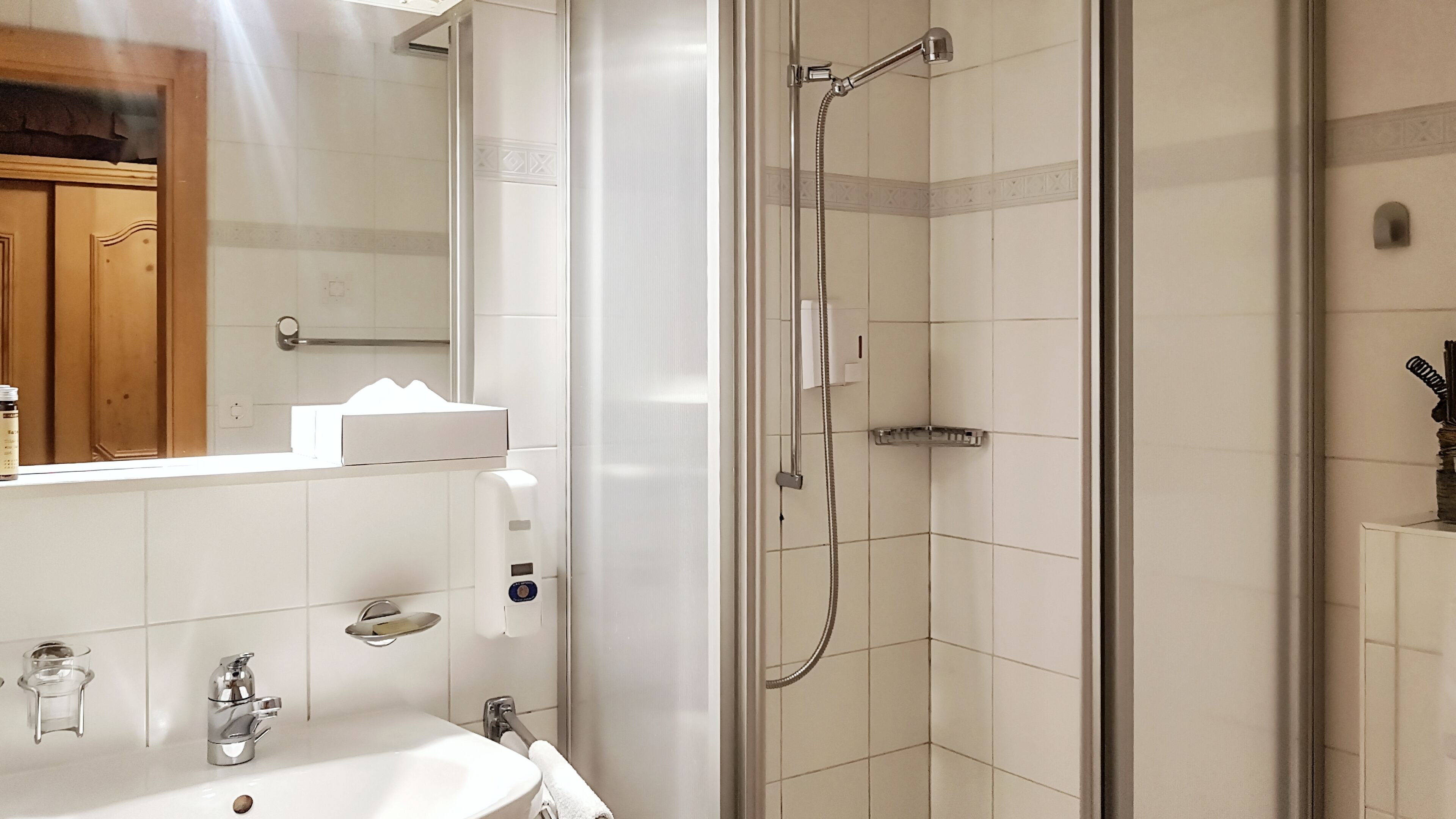 Un baño moderno con cabina de ducha de vidrio, un lavabo blanco y un espejo.