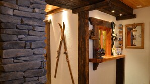 A stone wall, wooden beams, a mirror, and a shelf with various items. - Hôtel Restaurant LA CAMBUSE (Vex)