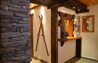 Una pared de piedra, vigas de madera, un espejo y una estantería con diversos objetos.