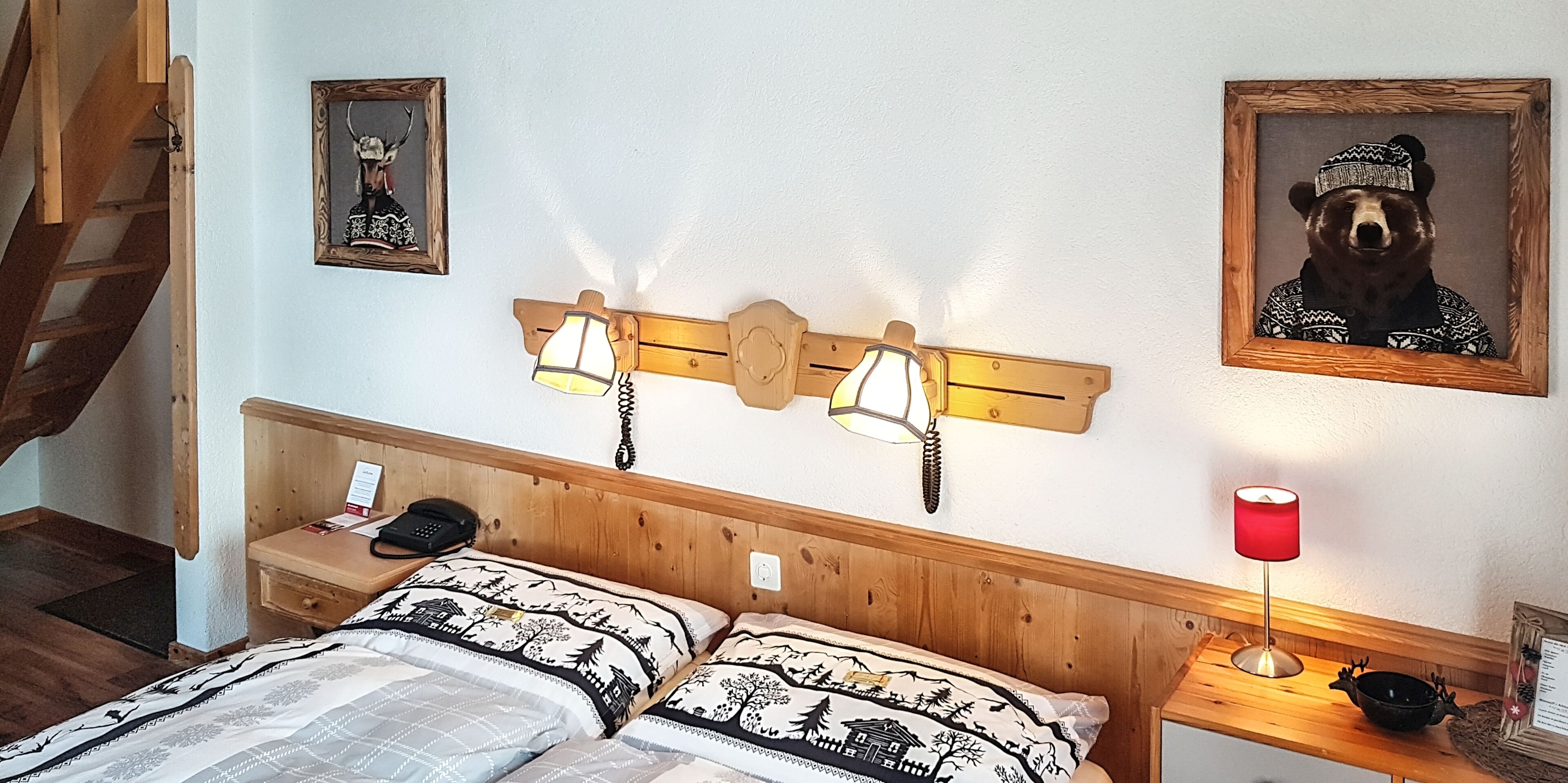 Una camera da letto con una testiera in legno, un letto con biancheria a motivi, un comodino con una lampada e un quadro appeso al muro.