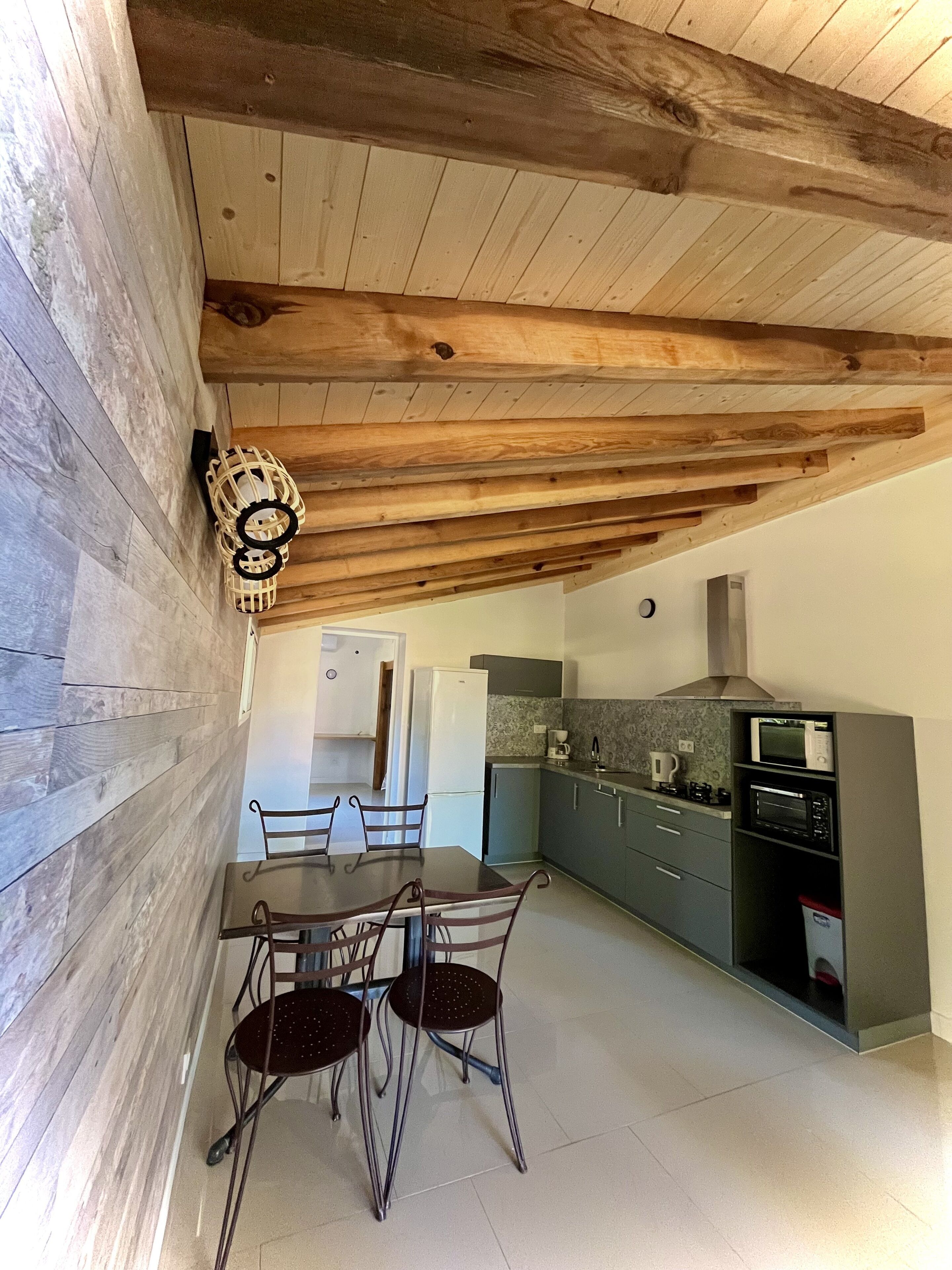Una cocina moderna con vigas de madera, una mesa de comedor con sillas y un microondas.