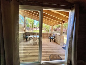 A covered patio with wooden flooring, a table, and chairs.