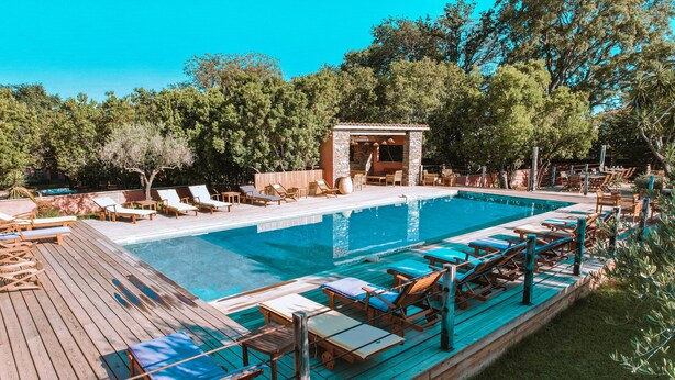 Una piscina con sillones de descanso y un muelle de madera.