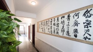 A corridor with a large calligraphy wall and potted plants.