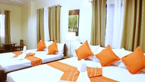 A hotel room with two beds, each with white linens and orange accents, a small table, and a chair. - Haisa Apartment (Coron)