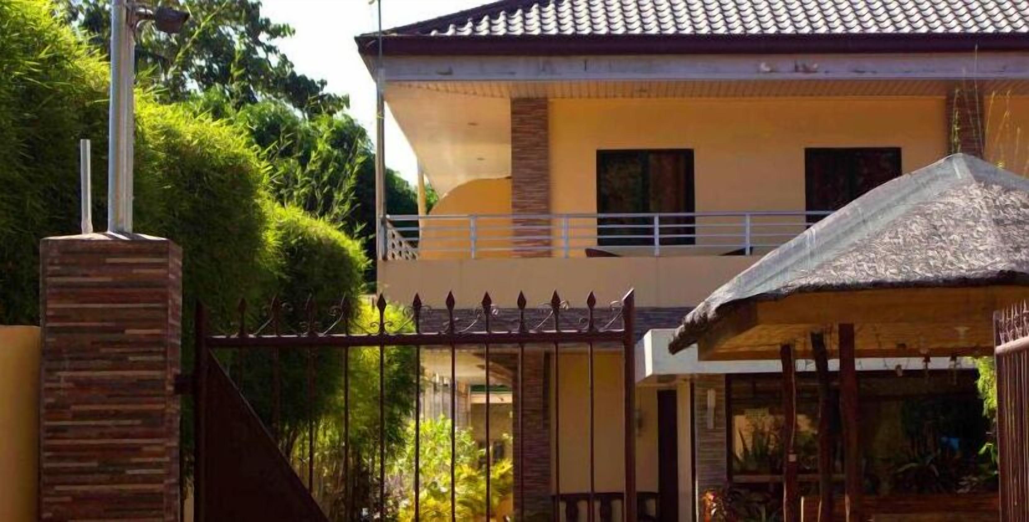 Una casa de dos pisos con balcón, portón y tejado de paja.