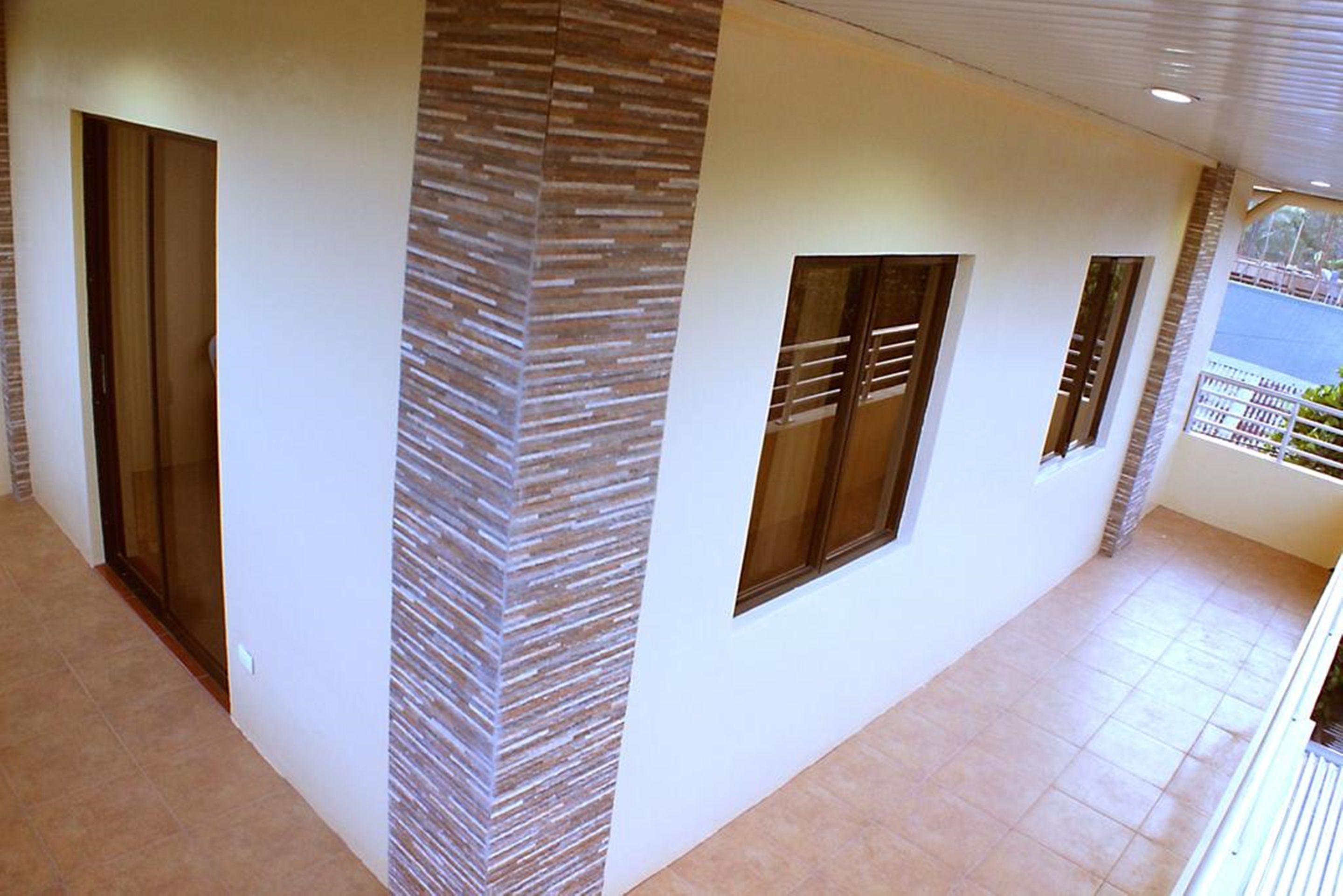 Un pasillo de diseño moderno, con una pared con textura y una puerta de cristal a la izquierda.