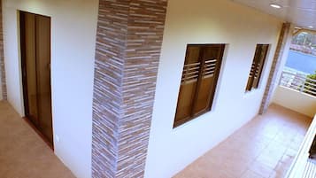 Un pasillo de diseño moderno, con una pared con textura y una puerta de cristal a la izquierda.