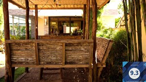 A wooden bench under a bamboo structure with a view of a building in the background. - Haisa Apartment (Coron)