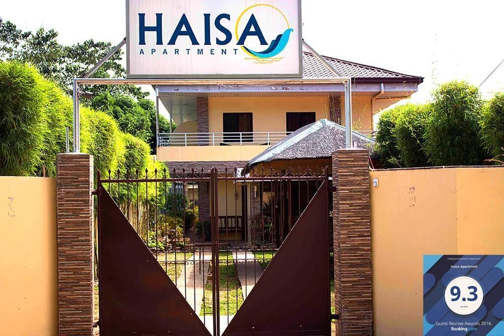 A gated entrance to Haisa Apartment with a clear view of the building's facade and a sign indicating a 9.3 guest review rating.
