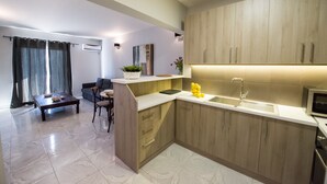 A modern kitchen with wooden cabinets, a built-in sink, and a dining area with a table and chairs. - Regalo Apartments (Lefkada)