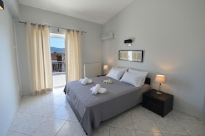 Ein Hotelzimmer mit einem Bett, zwei Nachttischlampen, einer Heizung, einem Fenster mit Vorhängen und einem gerahmten Bild an der Wand.