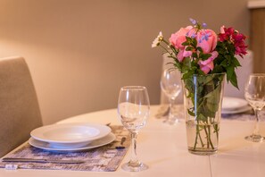 Ein Esstisch ist gedeckt mit Tellern, Besteck und einer Blumenvase.