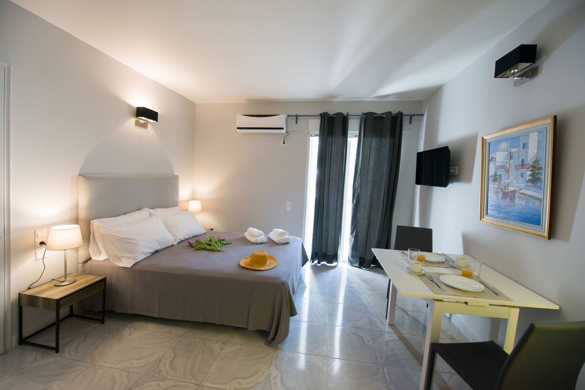 A hotel room with a bed, bedside table, and a dining area with a table and chairs.