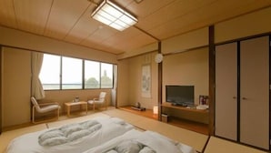 A traditional Japanese-style room with tatami flooring, a bed with a futon, a television, and a sliding door. - Centrale Hotel Kyotango (Kyotango)