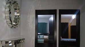 Une pièce avec un mur recouvert de miroirs, un lit, une table de chevet et une porte donnant sur une autre pièce.