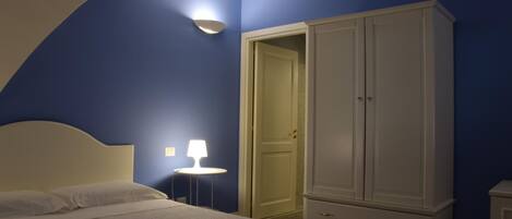 A bedroom with a bed, a wardrobe, and a nightstand with a lamp.