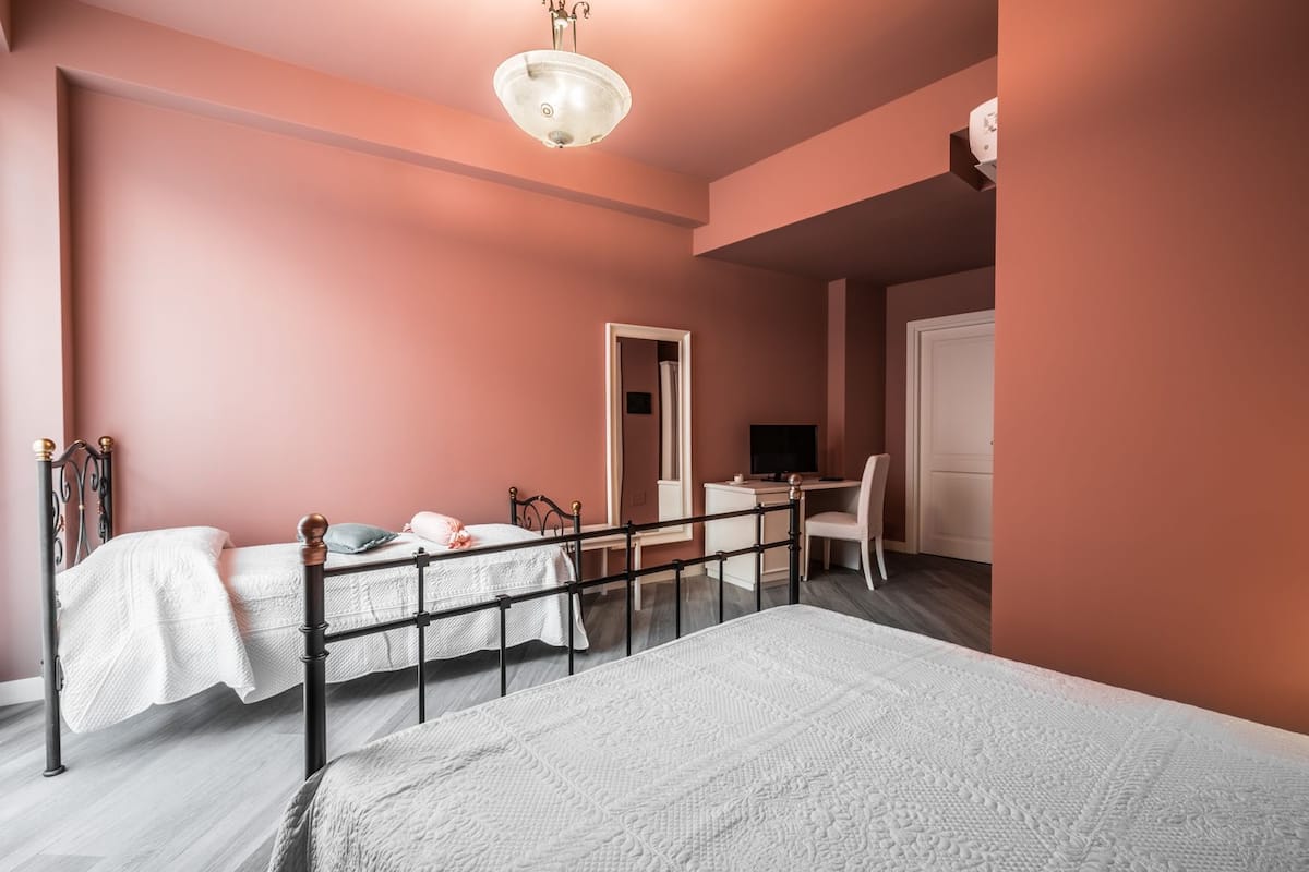 A bedroom with two beds, a desk, a chair, and a television.