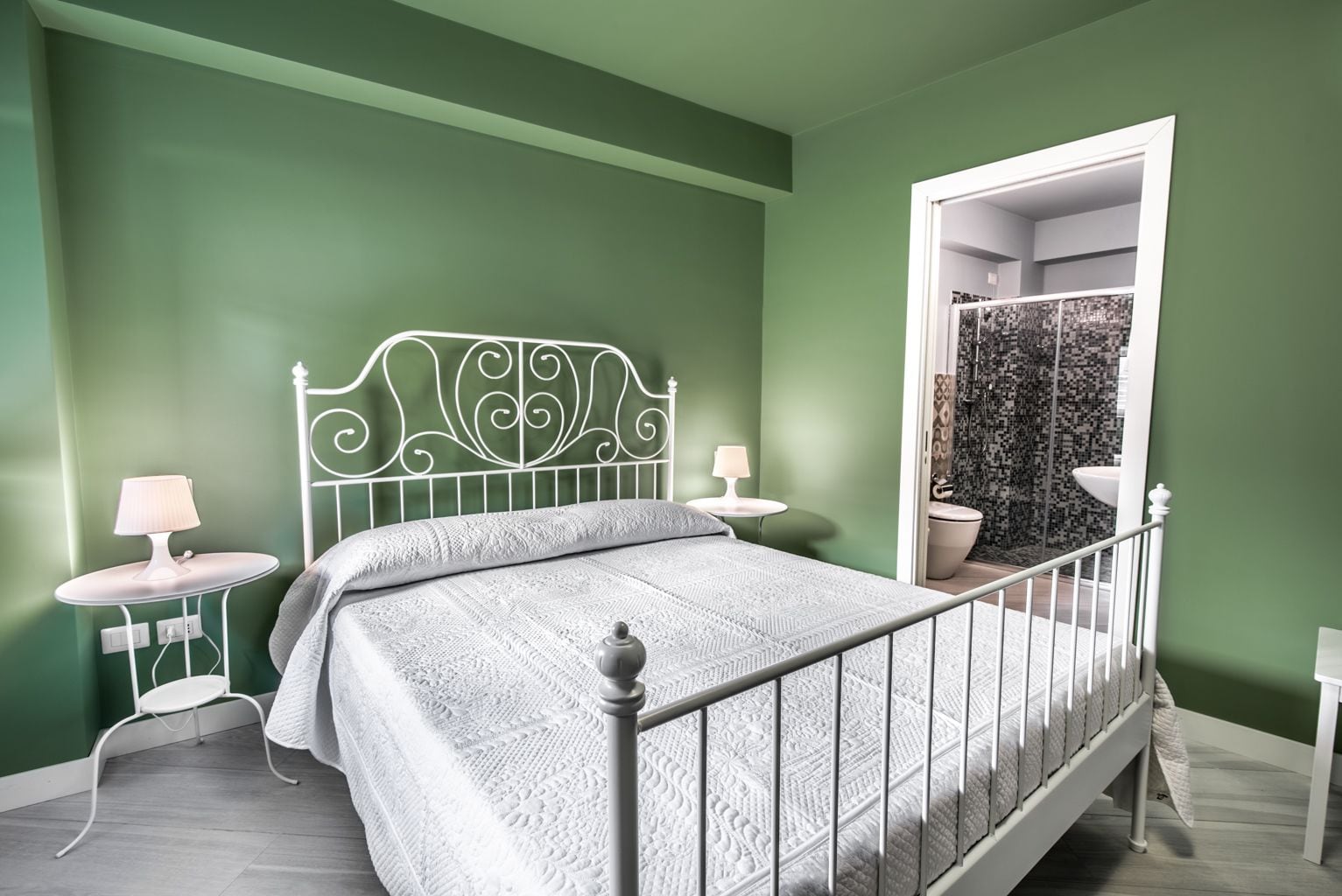 Un dormitorio con una cama, dos mesitas de noche y un baño visible a través de una puerta abierta.