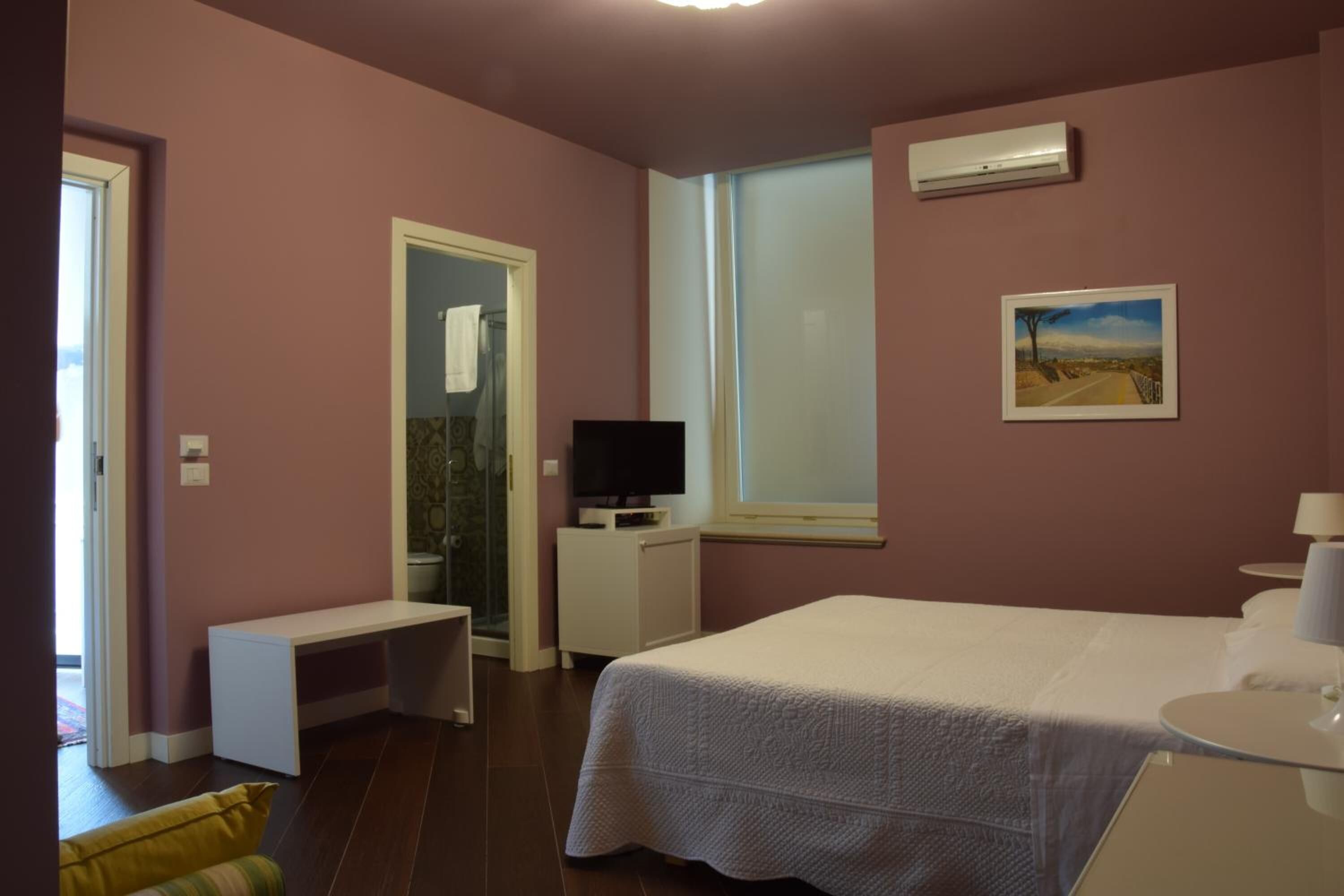 Un dormitorio con cama, escritorio, televisor y ventana.
