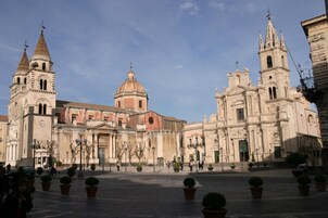 Una plaza histórica con una iglesia destacada, que cuenta con una cúpula y dos torres de campanas.