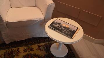 A white armchair and a small white table with a book on it.
