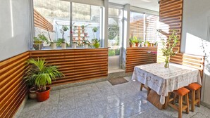 Una habitación moderna con un ventanal grande, paneles de madera, una mesa con mantel blanco y plantas en macetas.