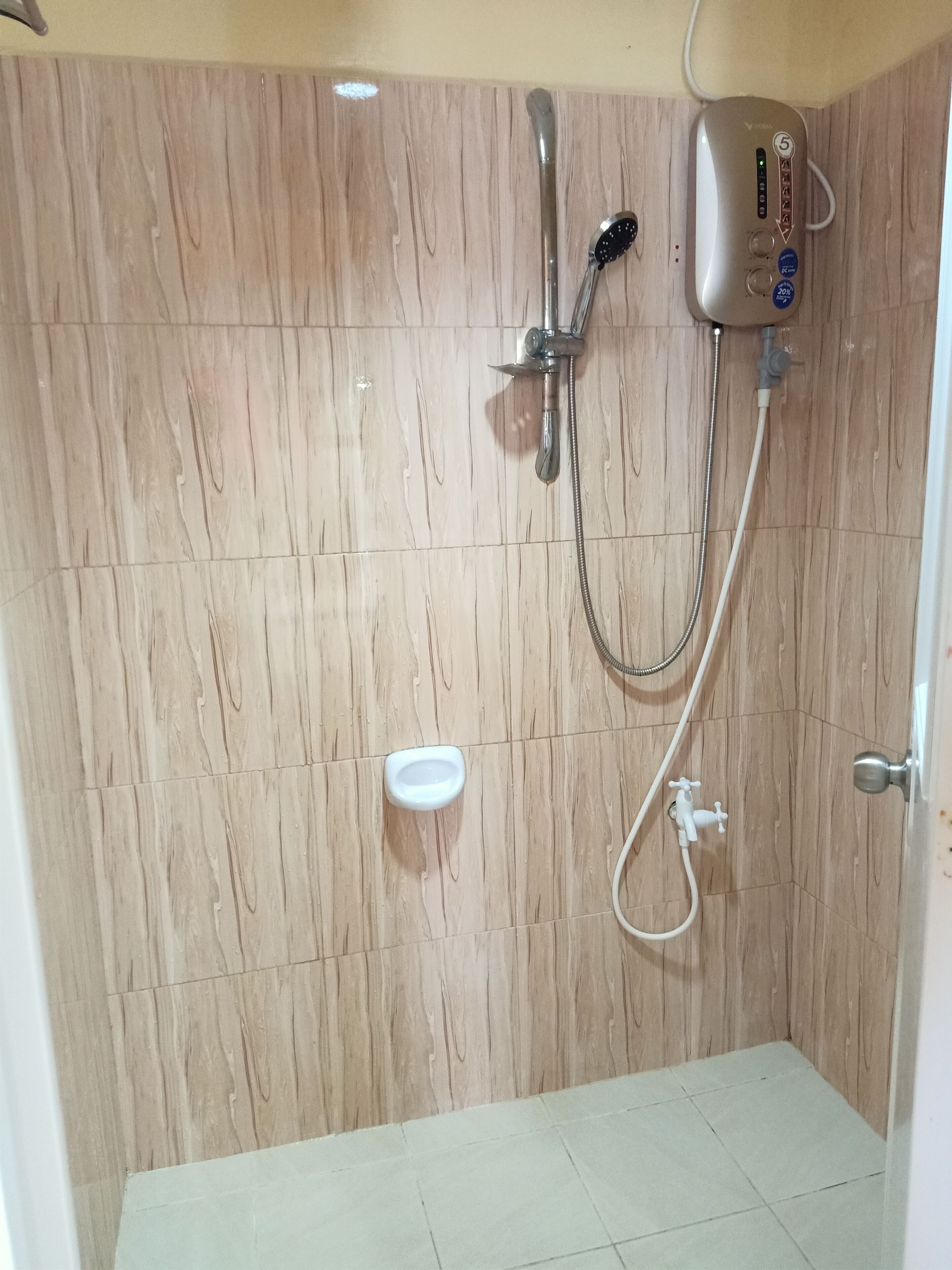 Una ducha con cabezal de ducha manual, grifo empotrado en la pared y manguera de ducha.