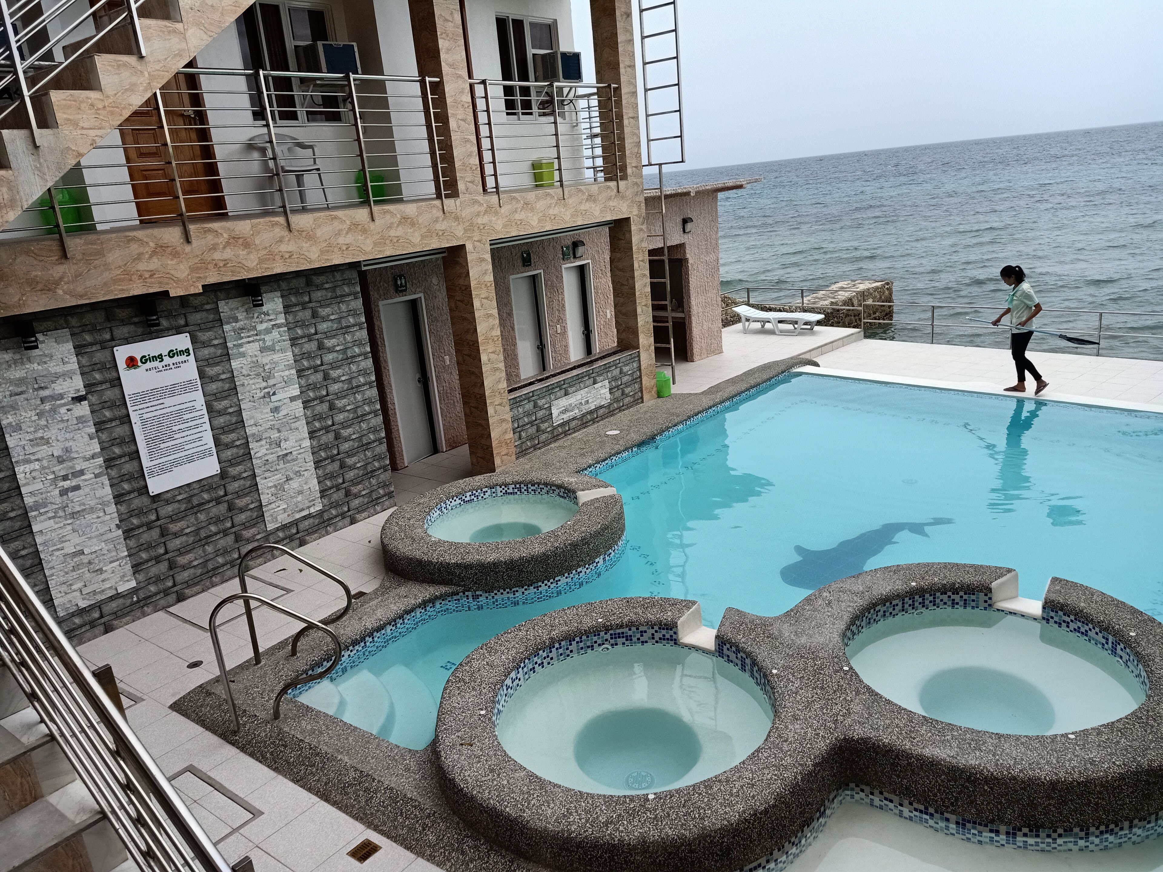 Un hotel con zona de piscina que incluye múltiples jacuzzis y vistas al mar.