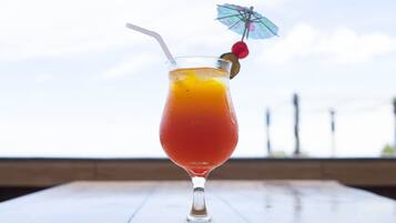 Un vaso de jugo de naranja con una pajita y un paraguas decorativo sobre una mesa de madera.