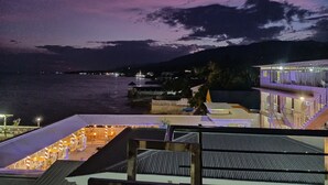A rooftop terrace with outdoor seating, overlooking a body of water and a distant shoreline.