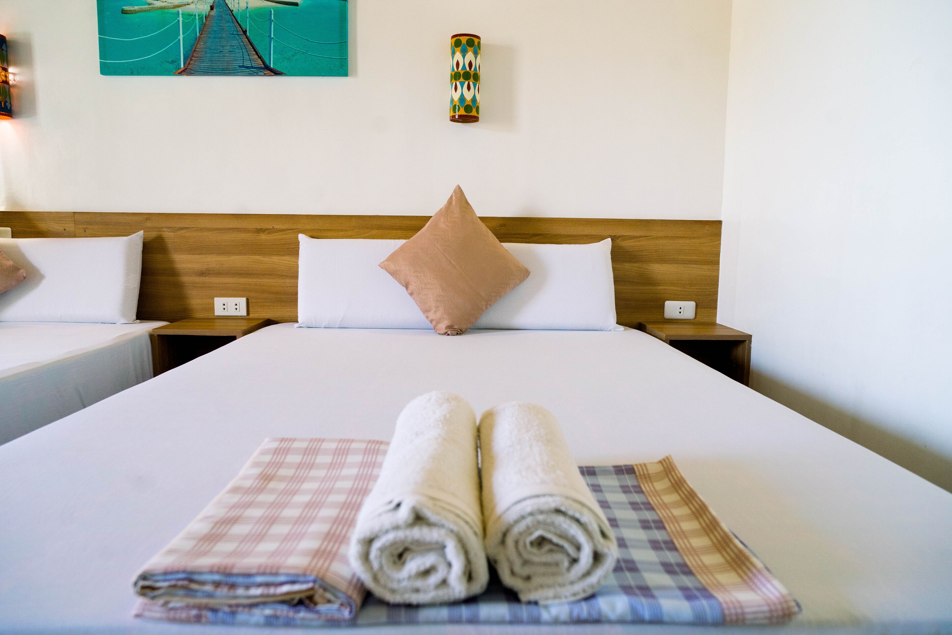 A hotel room with a large bed, two bedside tables, a headboard, and a wall-mounted lamp.