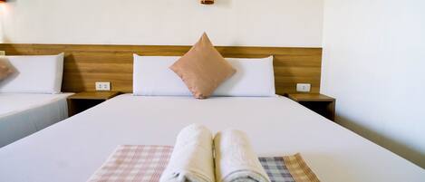 A hotel room with a large bed, two bedside tables, a headboard, and a wall-mounted lamp.