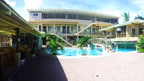 A hotel with a pool area, outdoor seating, and a multi-level building with a curved roof.