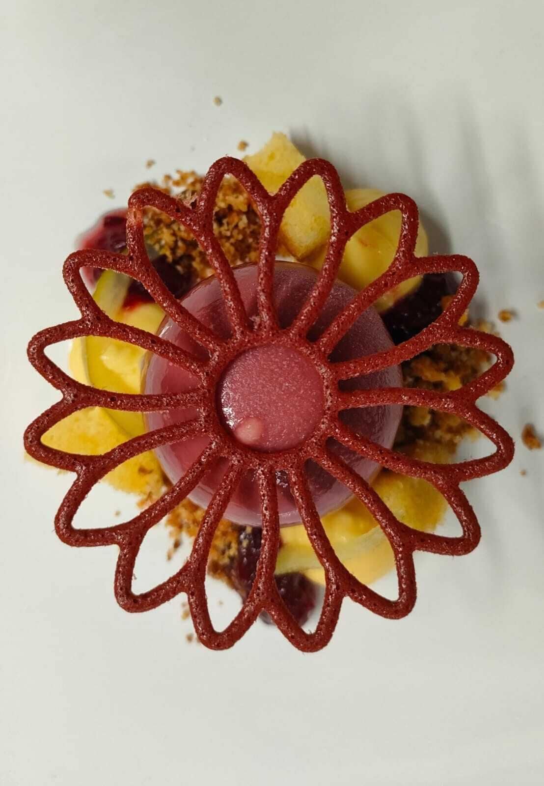 Een dessert met een rood, bloemachtig ontwerp op een wit bord.