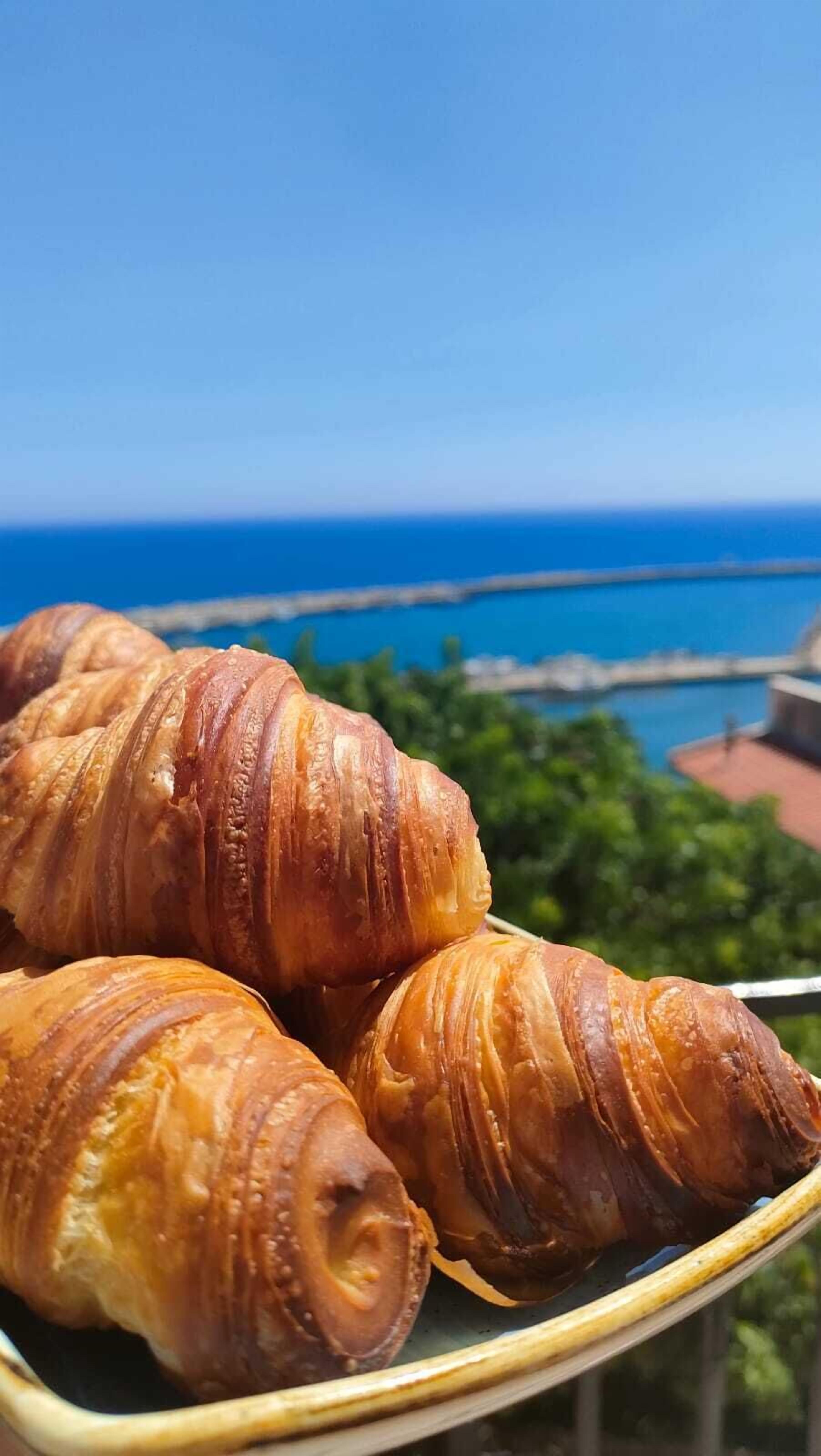 Croissants on a plate with a view of a bridge and the ocean in the background.