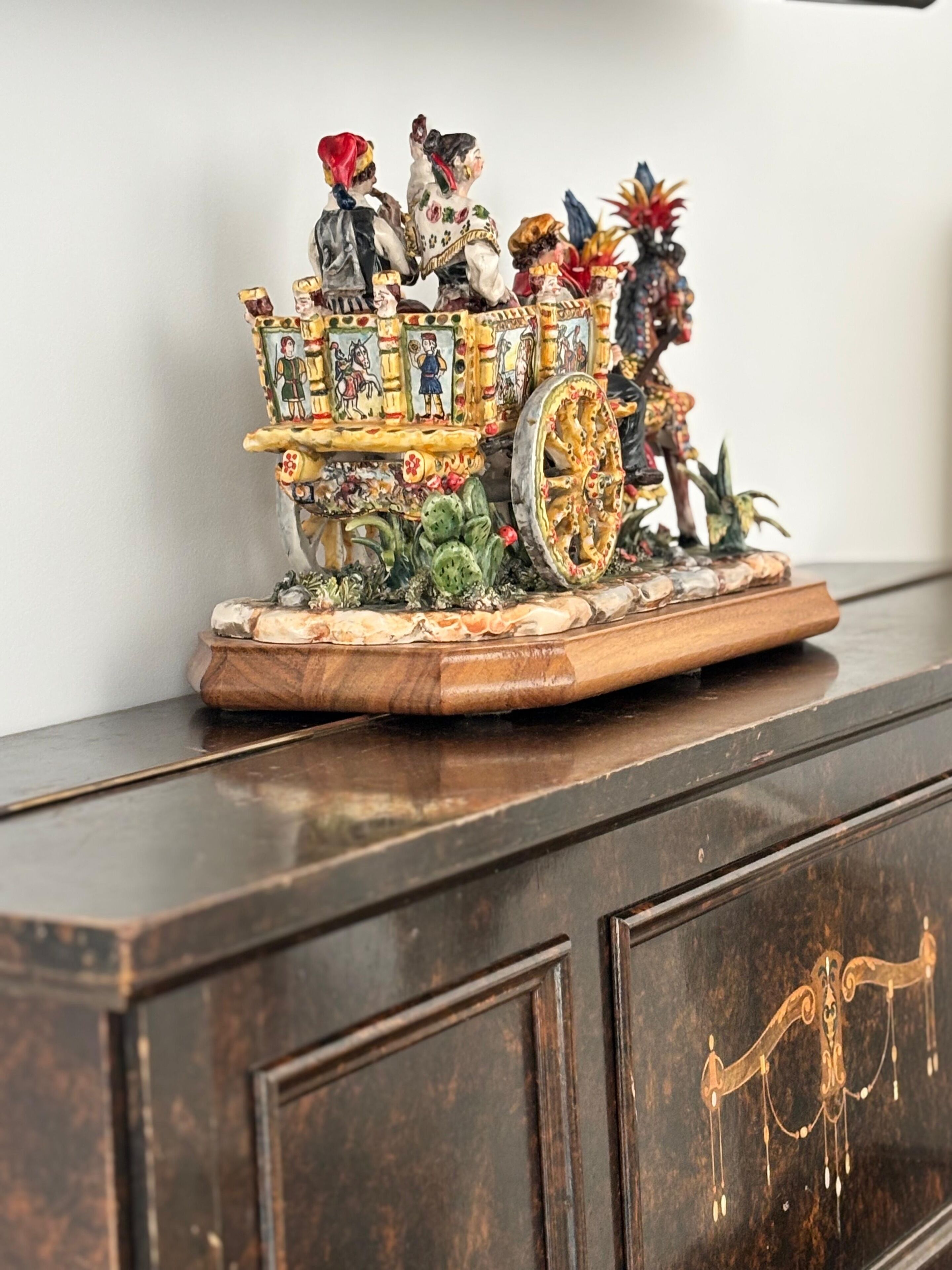A detailed miniature model of a decorated carriage with figures, placed on a wooden base.