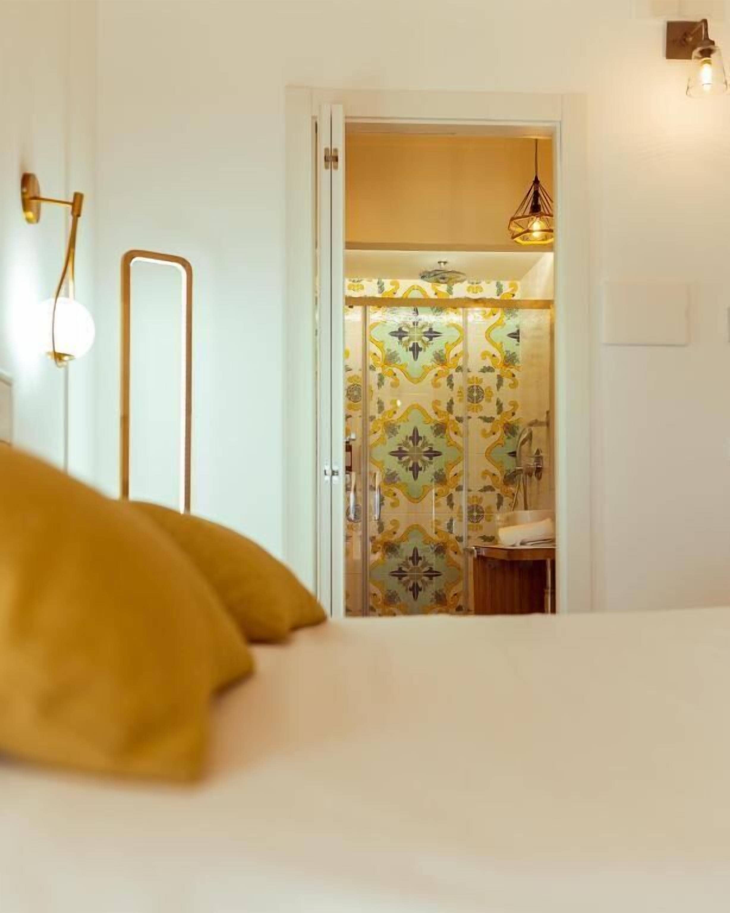 A hotel room with a bed, a mirror, a wardrobe with patterned doors, and a hanging light fixture.