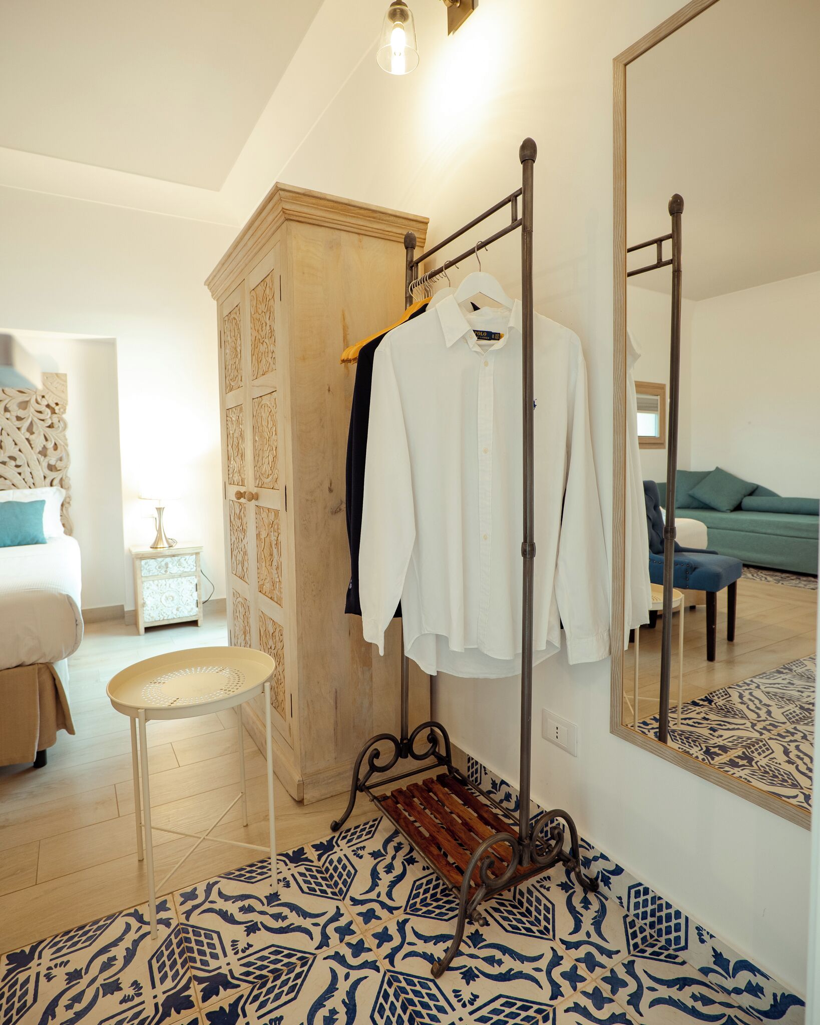 Une chambre à coucher comprenant un lit, une armoire, un portant à vêtements, une petite table et un sol à motifs.